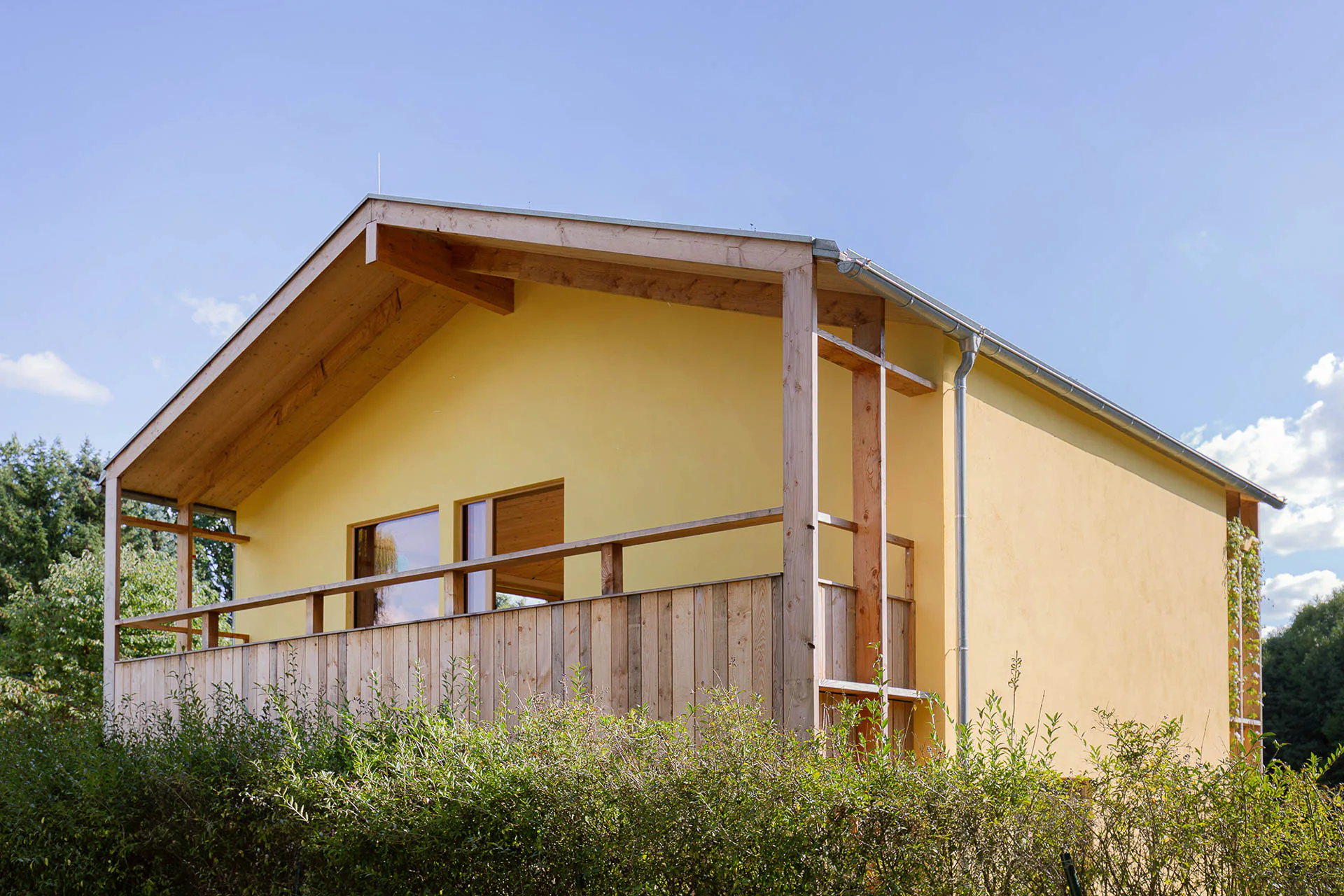 Der Balkon aus heimischer Lärche kragt aus dem Baukörper heraus, das weit vorstehende Dach schützt Fassade und Konstruktion vor Bewitterung. Der Kalkputz ist außen mit Silikatfarbe hydrophobiert.