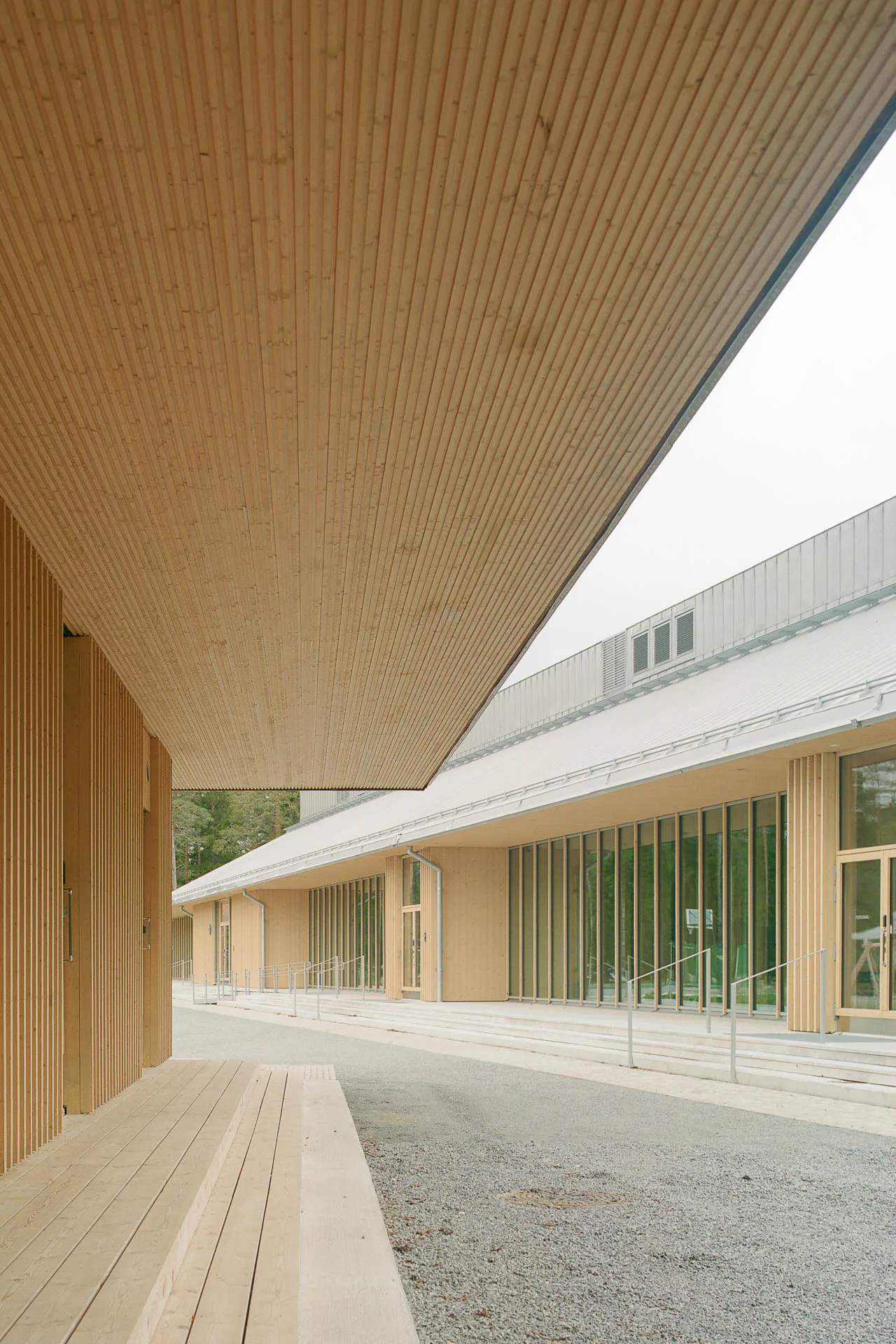 Breite Stufen um das Gebäude führen zu den Eingängen und Öffnungen in der Fassade. Der große Dachüberstand ermöglicht eine witterungsunabhängige Erweiterung des Innenraums nach außen.