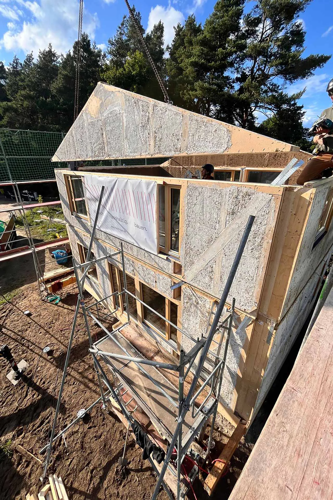 Vorgefertigtes Wandelement beim Einheben: Strohdämmung, Fenster und erste Putzschicht sind bereits im Werk eingebaut.