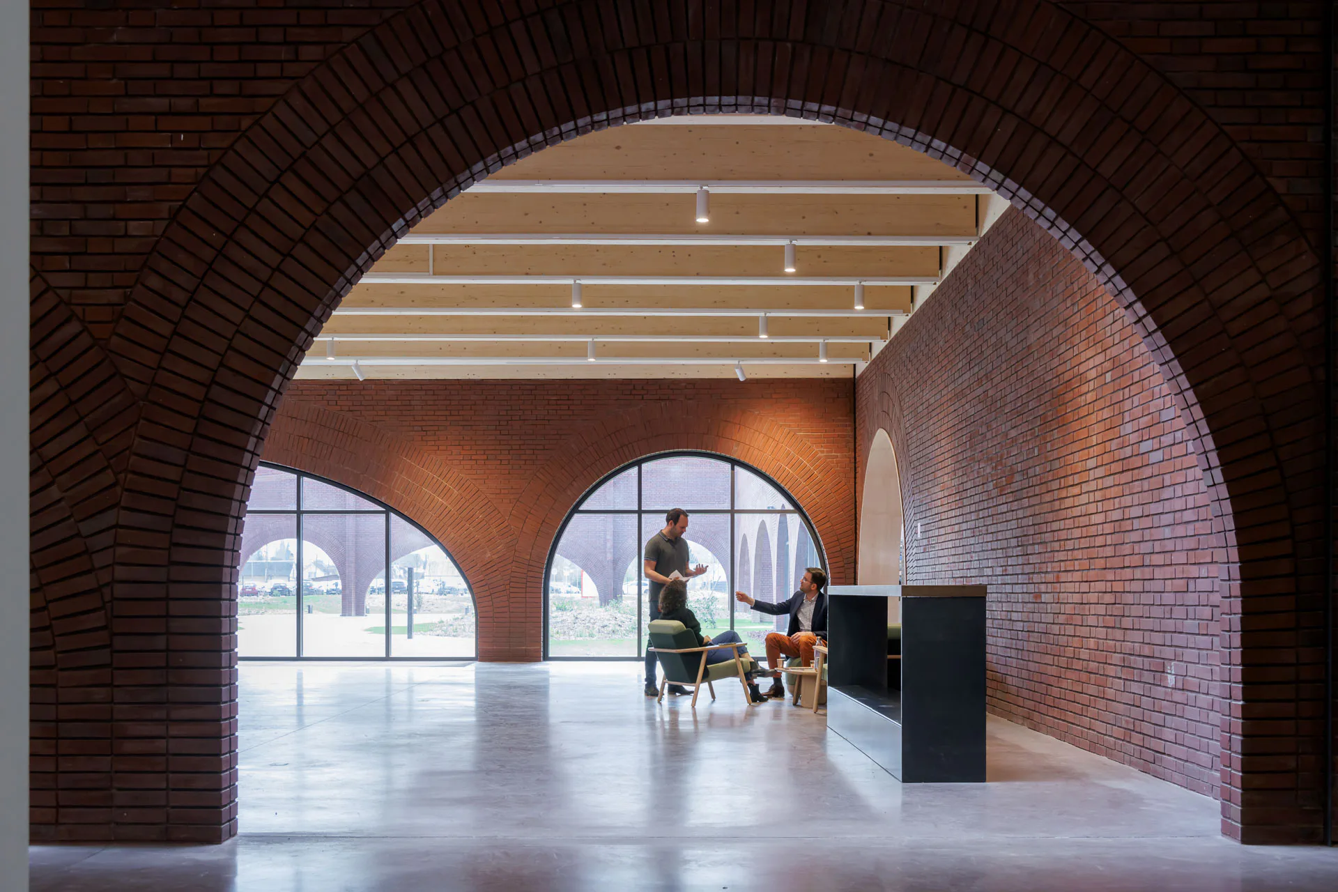 Werkstätten Hermès (2023): Schottenwände mit großen Bogenöffnungen strukturieren auch das Innere. Auf den Wänden liegt eine flache Holzdecke auf.