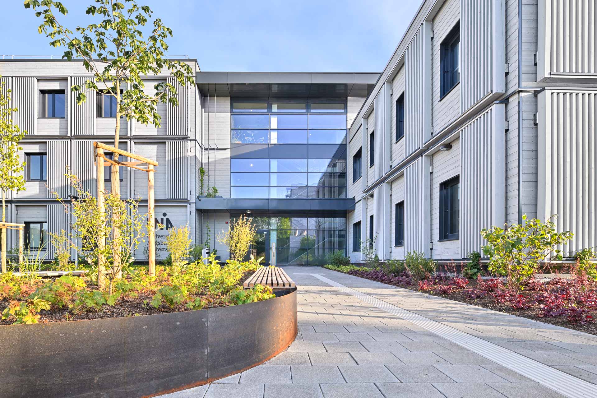 Der Büro- und Laborneubau auf dem Campus der Uni Augsburg besteht aus zwei funktional voneinander getrennten Baukörpern mit einem zweigeschossigen Labortrakt und einem dreigeschossigen Bürokomplex.