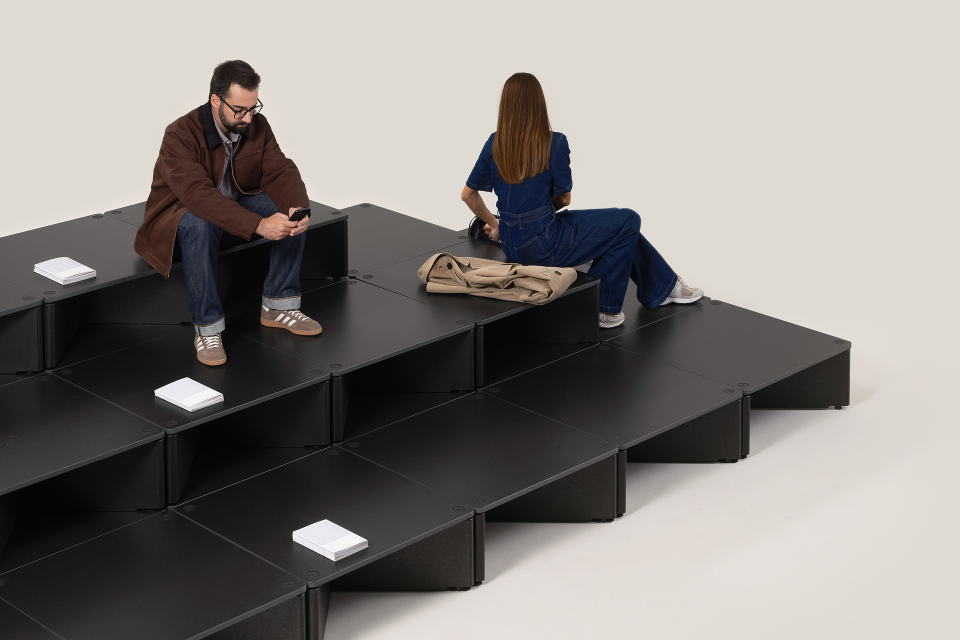 Aus den Plattformen entstehen je nach Anordnung Podeste, Sitzstufen oder Arbeitsinseln. Faltbare Sitzkissen verwandeln einzelne Module in Sitz- und Rückzugsbereiche.