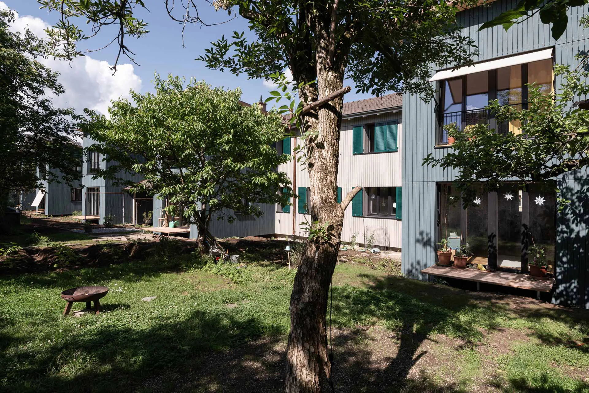 Mit grün lasierten Holzanbauten hat das Studio Balthasar Wirz die Wohngenossenschaft Wolfmatten bei Basel erweitert.