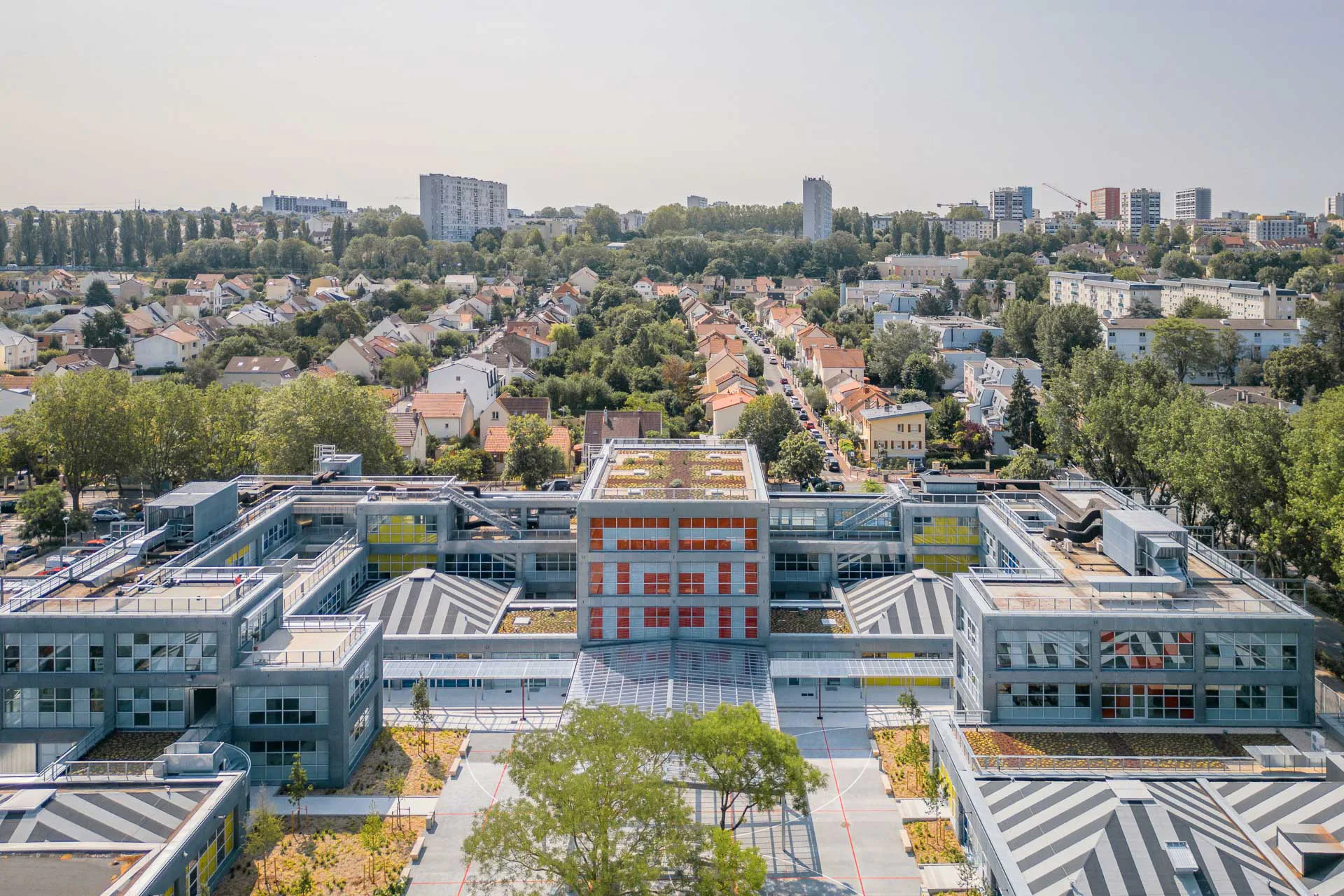 Das strenge Raster zieht sich erkennbar vom Grundriss über die Fassade. Knallbunte Fenster und schwarz-weiße Blockstreifen auf den Pyramidendächern evozieren den Geist der 1980er-Jahre.