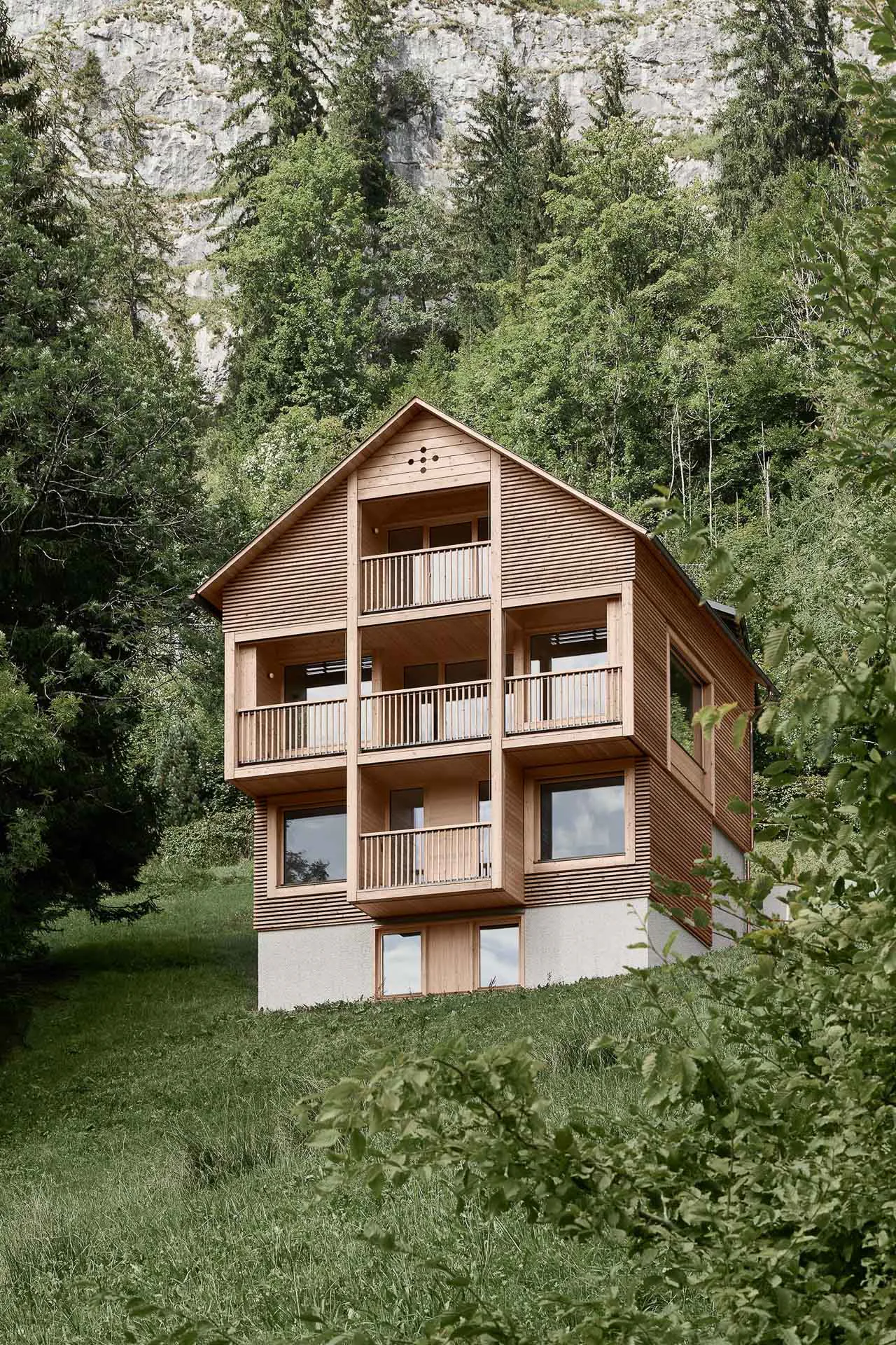 An einem steilen Hang sitzt auf dem massiven Sockel aus Stahlbeton der hölzerne Aufbau.