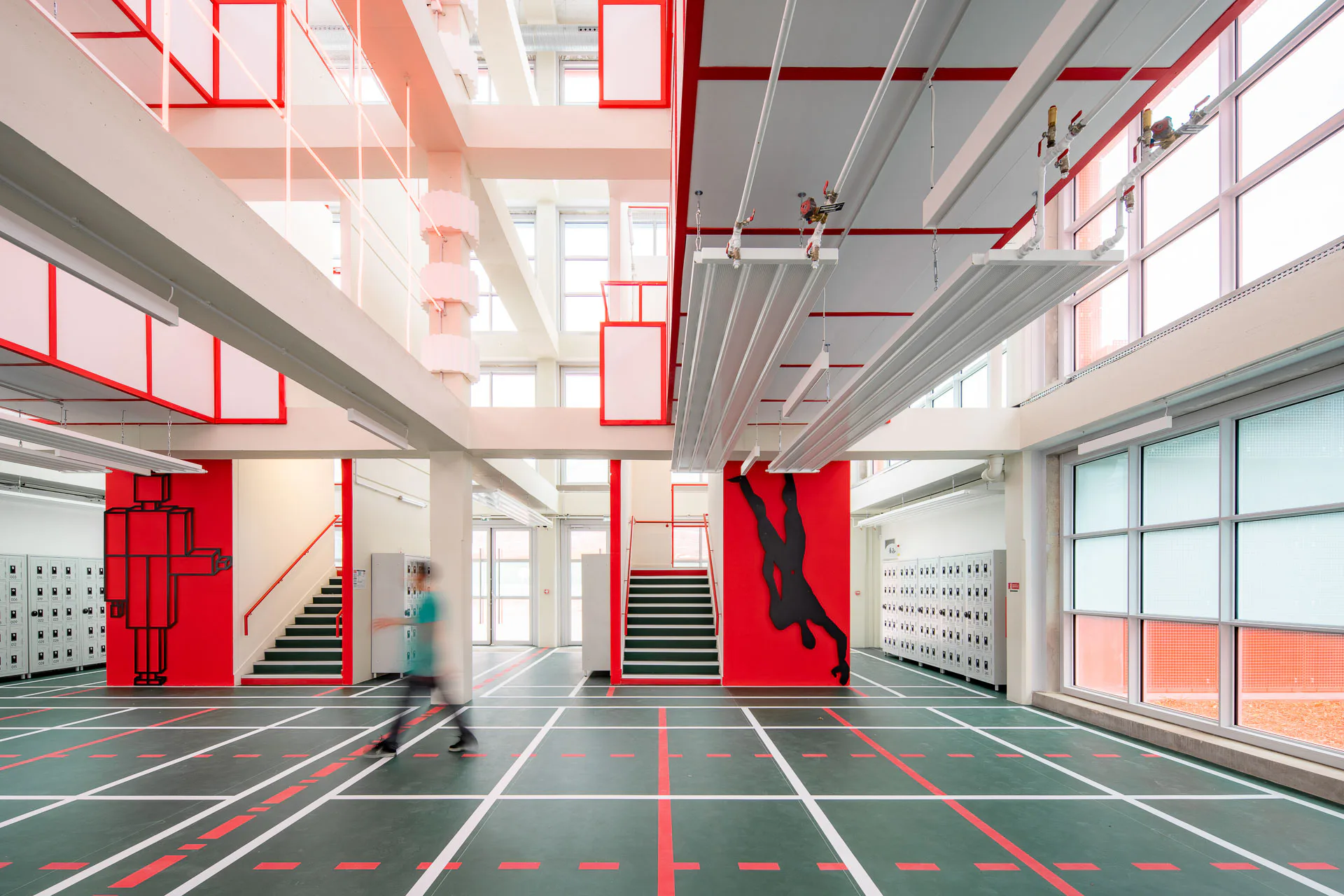In der Eingangshalle wird das strenge Raster besonders deutlich: es zieht sich vom Boden über die Fassade bis in den Luftraum. Zwei Treppen führen über Laufstege durch das gesamte Gebäude.