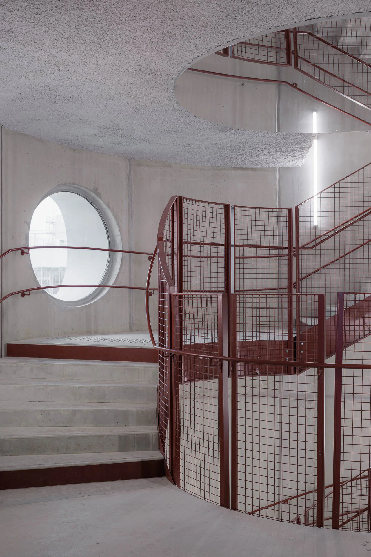 Das rote Treppengeländer steht im Kontrast zur materialhomogenen Betontreppe.