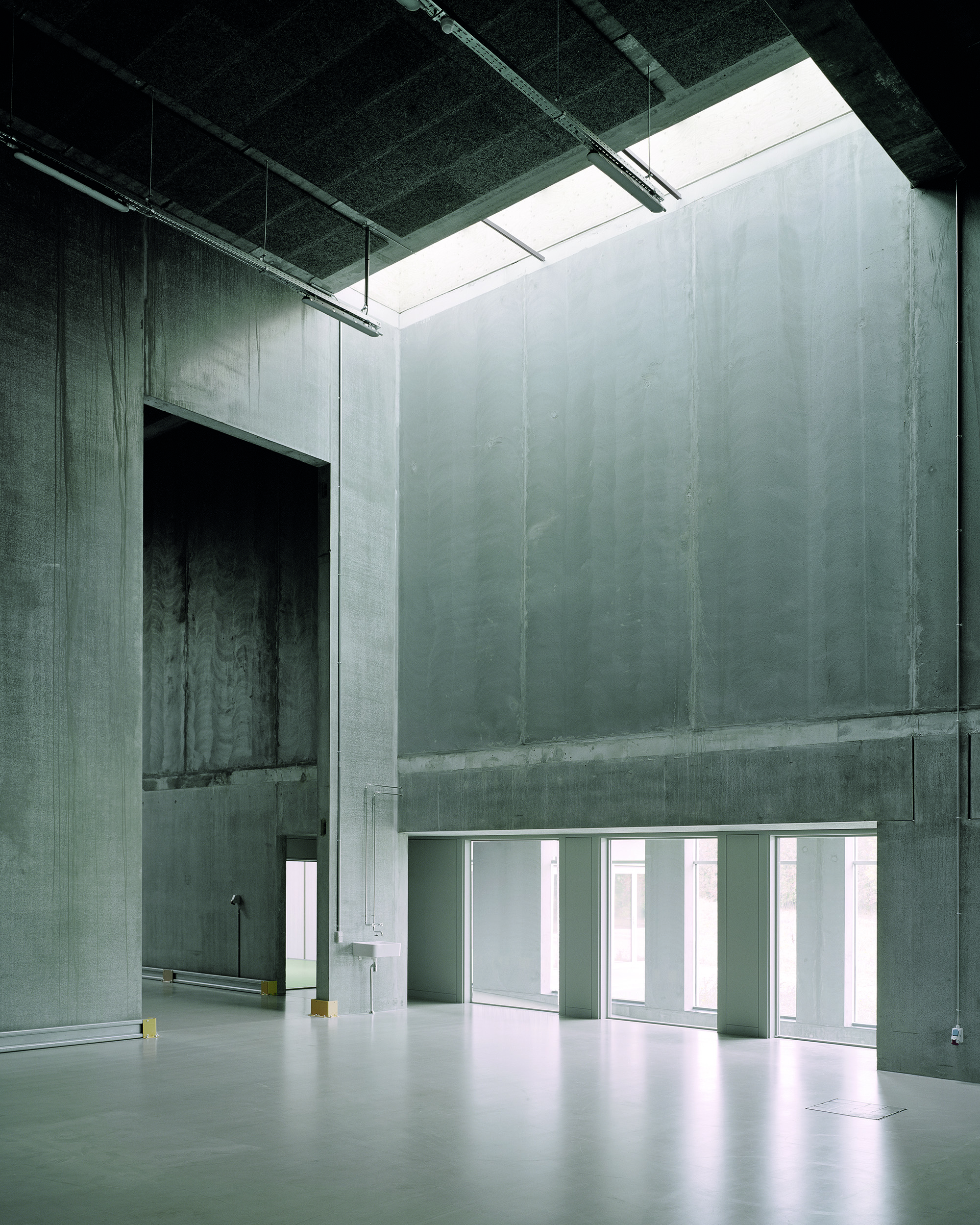 Skylights provide the more than nine metres tall hall with daylight. Spanning across the space, reinforced concrete beams support the precast concrete ceilings.