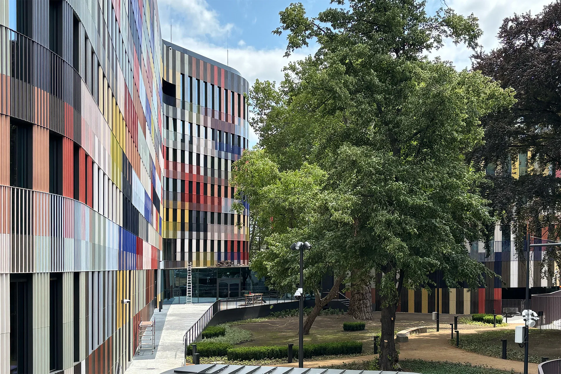 Das Grundstück ist äußerst beengt für das umfangreiche Raumprogramm. Immerhin ist es den Architekten gelungen einen kleinen Park im Innenhof mit altem Baumbestand zu erhalten.